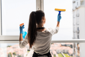 Mujer realizando la limpieza de vidrios en un apartamento.