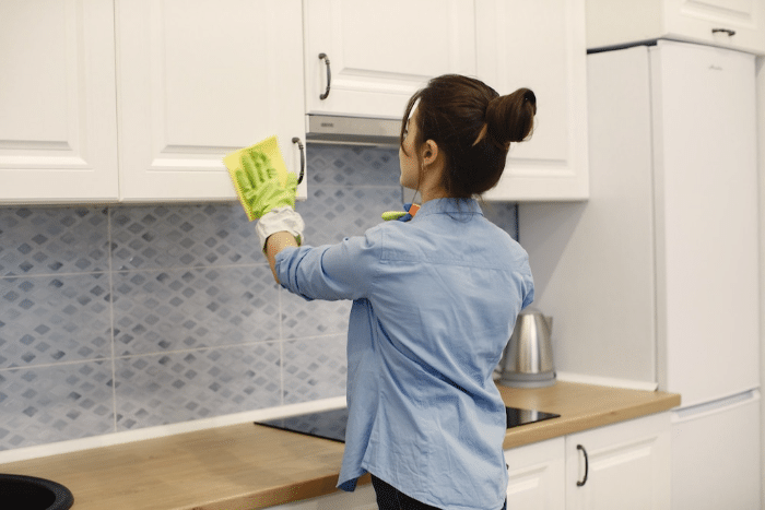 Mujer limpiando las superficies de los muebles de la cocina del apartamento turístico.